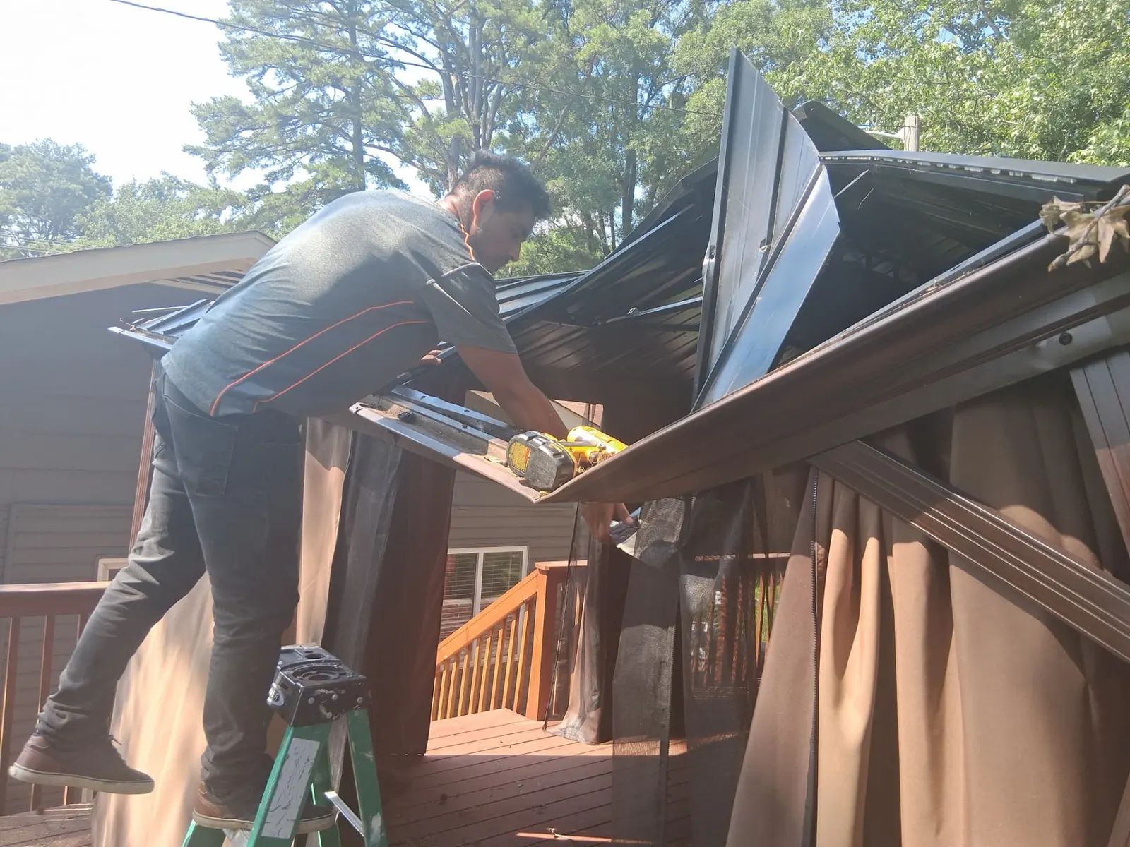Crew member disassembling a metal gazebo roof on a Charlotte, NC deck